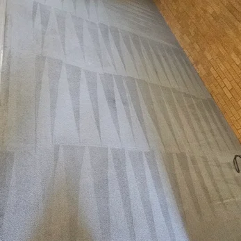 Close view of cleaning stripes on grey carpet beside a brick wall